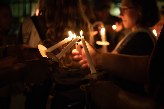 Group of people holding lit candles at night